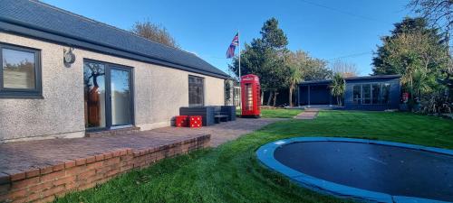 uma casa com uma cabine telefónica vermelha ao lado de um quintal em Laighdykes Guest Cottage em Saltcoats