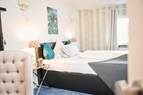 um pequeno quarto com uma cama e uma cadeira em Hotel Haus Rödgen em Wilnsdorf