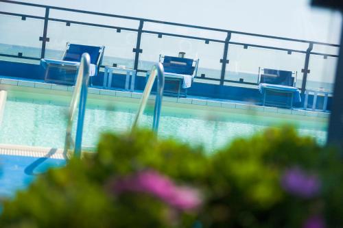 a swimming pool with blue chairs in the water at Hotel Royal in Fermo