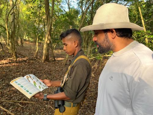 a man and a boy are looking at a book at Big Game - Wilpattu by Eco Team in Wilpattu