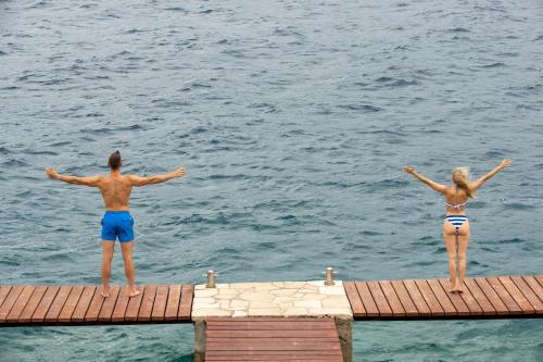 zwei Menschen stehen auf einem Steg im Wasser in der Unterkunft TUI BLUE Kalamota Island - All Inclusive in Dubrovnik