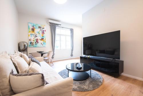 a living room with a couch and a flat screen tv at PORT CITY HAIFA - Authentic German Colony Apartments in Haifa