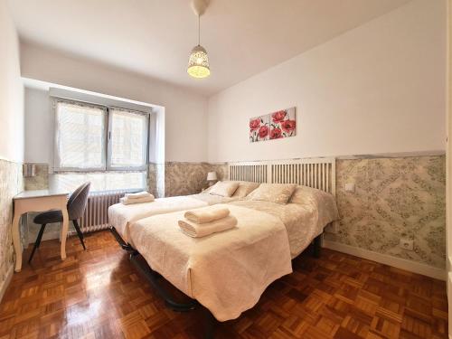 a bedroom with two beds and a desk in it at APARTAMENTO Delia in Gijón