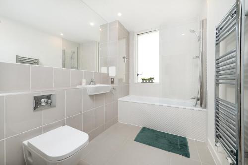 a white bathroom with a toilet and a sink at Chic London 1 bedroom flat in London