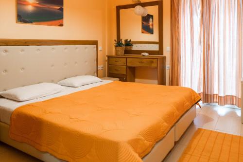 Antheia Apartments في آغيوس ستيفانوس: غرفة نوم مع سرير وبطانية برتقالية