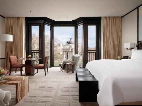 ロンドンにあるThe Peninsula Londonのベッド、テーブル、椅子が備わるホテルルームです。