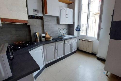 une cuisine avec des placards blancs et une grande fenêtre dans l'établissement Appartement spacieux et agréable, à Marseille
