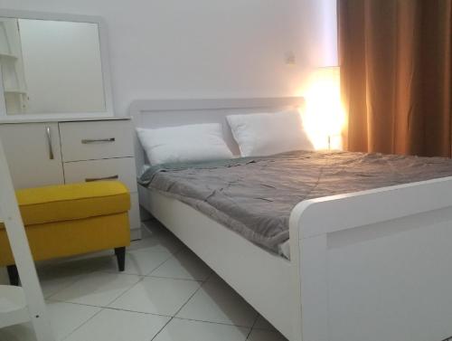 - une chambre avec un lit blanc et une chaise jaune dans l'établissement Amazing One-Bedroom Villa TownHouse, à Dubaï
