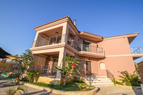 una casa rosa con balconi e fiori di Nektarios & Eftychia Suites a Ambelókipoi