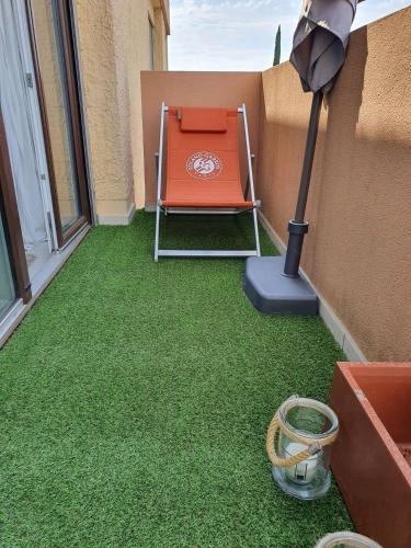 patio z krzesłem, parasolem i trawą w obiekcie Le Vallis Curans w miejscowości Saint-Raphaël