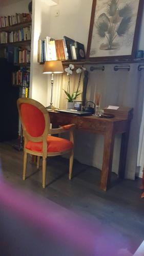 a wooden desk with a red chair and a lamp at Le Vallis Curans in Saint-Raphaël