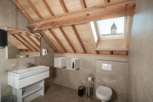een badkamer met een wastafel, een toilet en een raam bij Craywinckelhof Streekbelevingscentrum in Lubbeek