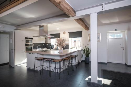 a kitchen with a large island with bar stools at Craywinckelhof Streekbelevingscentrum in Lubbeek