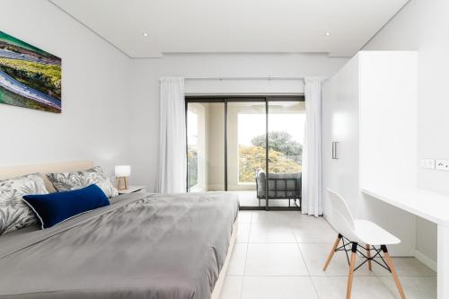 a white bedroom with a large bed and a chair at Modern 2 bedroom apartment - Soleia 2 Apartment A9 in Pereybere
