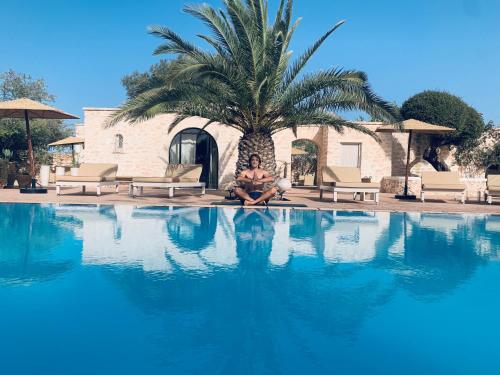 a man sitting next to a palm tree next to a swimming pool at Maison Belhazar in Essaouira