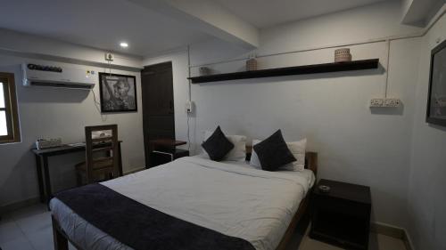 a bedroom with a bed with white sheets and pillows at Anjoned Hostel & Cafe in Anjuna