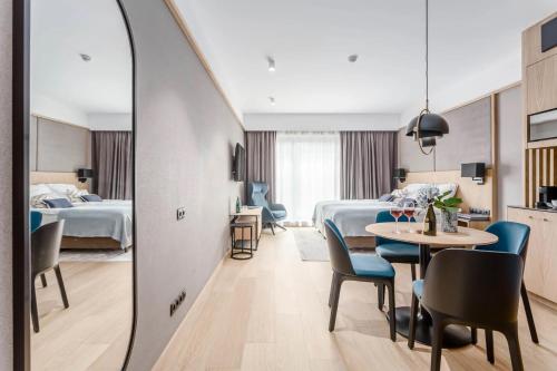 a hotel room with two beds and a table and chairs at Deo Plaza Old Town Gdańsk - Praia Apartaments in Gdańsk