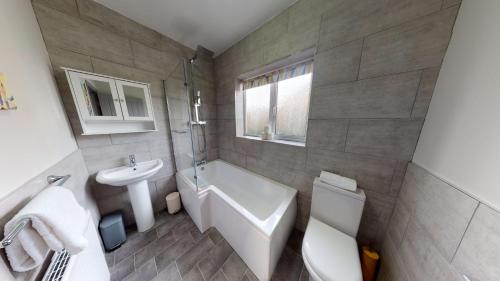 een badkamer met een wastafel, een bad en een toilet bij South Drive Bungalow in Middlesbrough