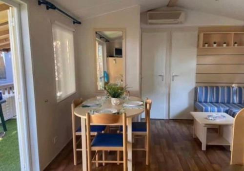 une petite cuisine et salle à manger avec une table et des chaises dans l'établissement Agde MOBIL HOME 3CH-SECTEUR VIP GARDEN VILLAGE CLUB PARC ACQUATIQUE, au Grau-dʼAgde