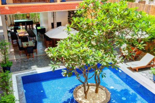 a swimming pool with a tree next to a house at House Boutique Eco Hotel in Phnom Penh