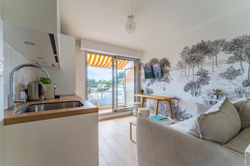 Il dispose d'une cuisine et d'un salon avec un canapé et un évier. dans l'établissement L'Embarcadère - Petit paradis 1ère ligne vue mer, à Arcachon