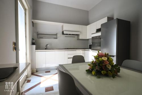 a kitchen with a table with a bouquet of flowers on it at LA PUTEA SUITE in Lecce