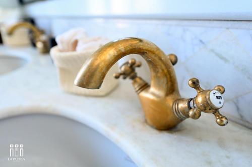 a bathroom sink with a brass faucet at LA PUTEA SUITE in Lecce