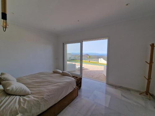 um quarto com uma cama e uma grande janela de vidro em Villa avec vue exceptionnelle em Tânger