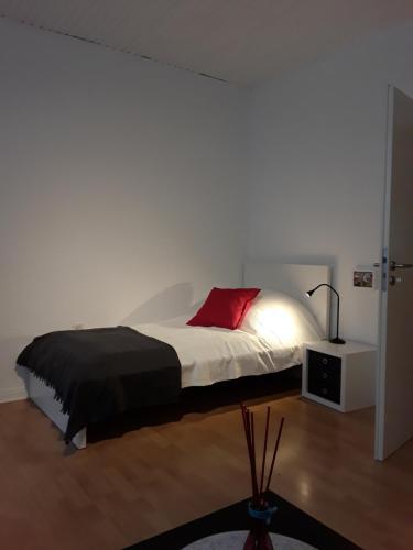 ein Schlafzimmer mit einem Bett mit einem roten Kissen in der Unterkunft TOP! möbliertes Apartment mit Parkplatz Nähe Messe Essen in Mülheim an der Ruhr