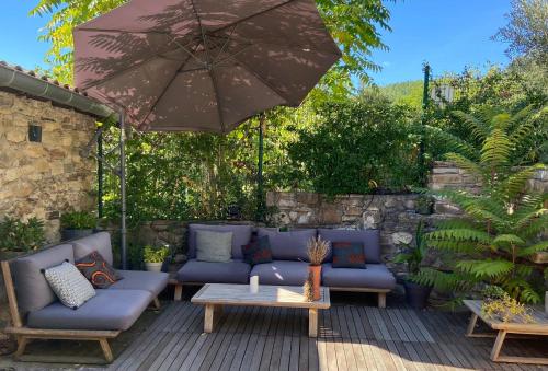 un patio con sofás azules y una sombrilla en MAISON ST LAURENT, en Olargues