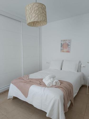 Un dormitorio blanco con una cama con toallas. en SHERRY SUITES VIII Apartamentos PARKING GRATUITO, en Jerez de la Frontera