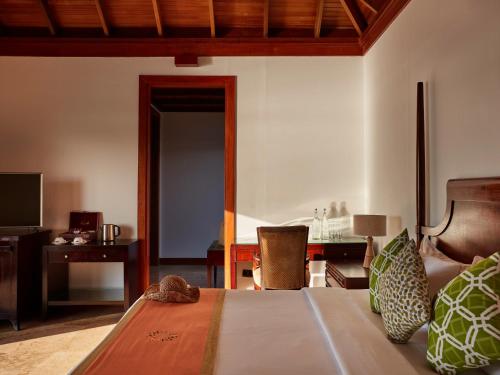 a bedroom with a bed and a desk and a chair at Sun Siyam Olhuveli in South Male Atoll