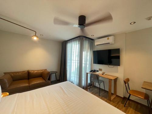 a bedroom with a bed and a couch and a tv at karaarom hotel in Bangkok