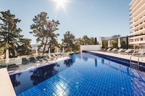 uma piscina com cadeiras e um edifício em Hotel Budva em Budva
