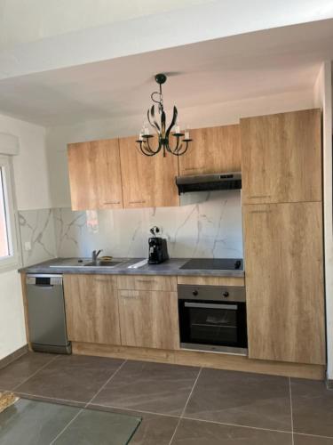 une cuisine avec des placards en bois et un lustre dans l'établissement Gîte - Les Salons du Bastier, à Ginasservis