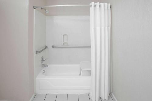 a bathroom with a tub and a shower curtain at Days Inn by Wyndham Denham Springs-Baton Rouge East in Denham Springs