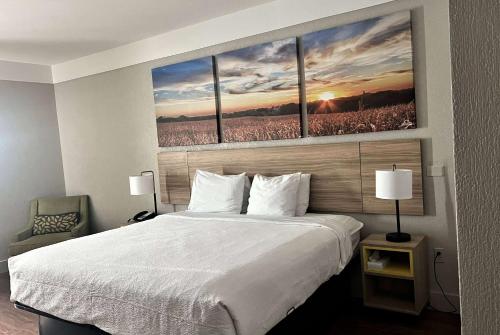 a bedroom with a bed with three paintings on the wall at Days Inn by Wyndham Denham Springs-Baton Rouge East in Denham Springs