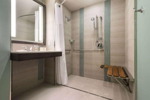 a bathroom with a shower and a sink and a mirror at Wyndham Grand Jupiter at Harbourside Place in Jupiter
