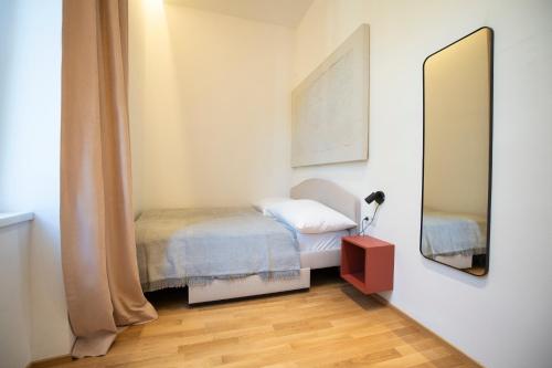 een kleine slaapkamer met een bed en een spiegel bij 2-rooms spacious apartment in a vibrant cozy area in Wenen