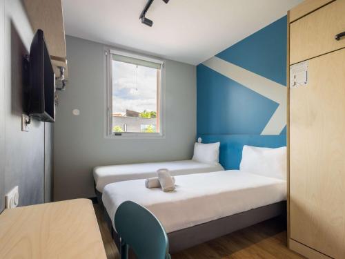 um pequeno quarto com 2 camas e uma janela em ibis budget Nanterre la Defense em Nanterre