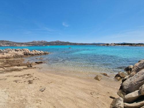 a beach with rocks and the ocean on a clear day at Affittimoderni La Maddalena - MADA14 in La Maddalena
