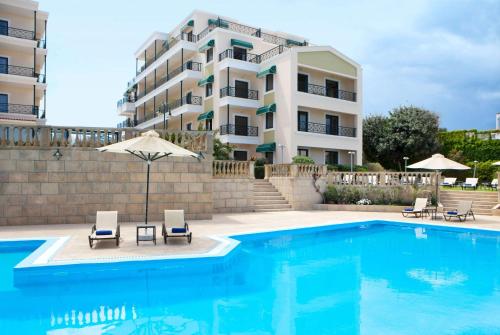 une piscine avec deux chaises et un bâtiment dans l'établissement Ramada by Wyndham , Athens Club Attica Riviera, à Mati