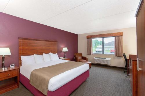 a hotel room with a large bed and a window at AmericInn by Wyndham New London in New London