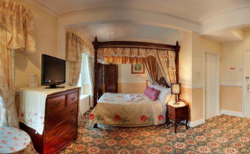 a bedroom with a bed and a tv in it at The Cumberland in Llandudno