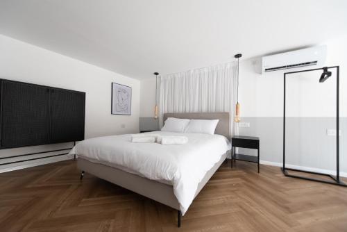a bedroom with a large white bed and a tv at PORT CITY HAIFA - Urbanic Loft in the Heart of Haifa's Downtown in Haifa