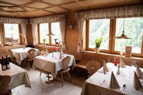restauracja ze stołami, krzesłami i oknami w obiekcie Gasthof Innerwalten w mieście San Leonardo in Passiria