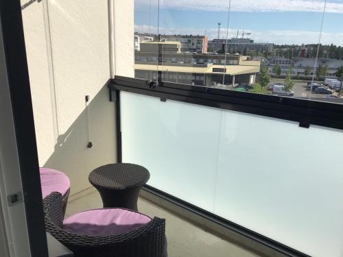 a balcony with a pink chair and a view of a city at Lovely 2R apartment in Oulu