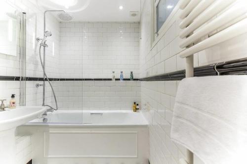 a white bathroom with a sink and a bath tub at Spacious Soho Home On Quaint Cobbled Street in London