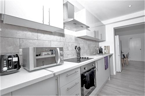 een witte keuken met een magnetron en een spoelbak bij Dunamis Staycation 5 in Croydon