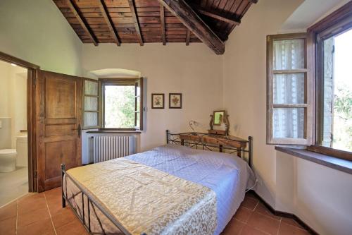 um quarto com uma cama num quarto com janelas em Casavecchia by PosarelliVillas em Pieve a Presciano
